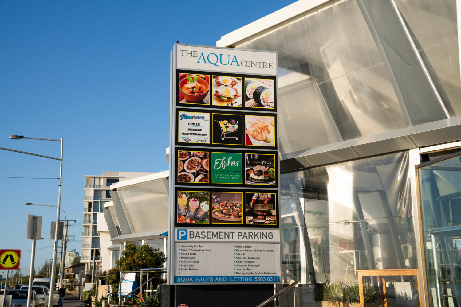 A sign saying "The Aqua Centre" and showing logos and photos of the restaurants and other facilities within the PARK SHORE lifestyle development precinct.